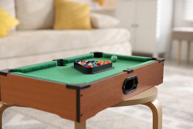 Photo of Many colorful billiard balls in triangle rack on green table indoors, closeup