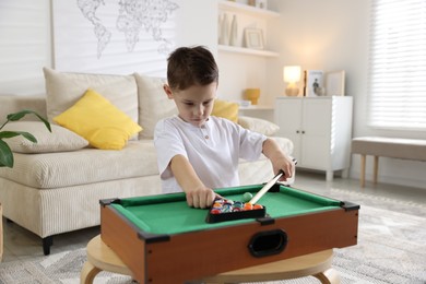 Photo of Cute little boy playing billiards at home