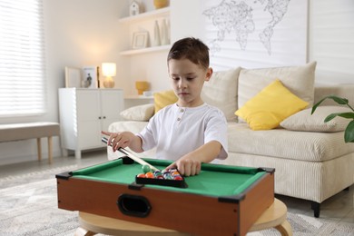 Photo of Cute little boy playing billiards at home