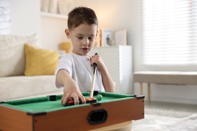 Photo of Cute little boy playing billiards at home