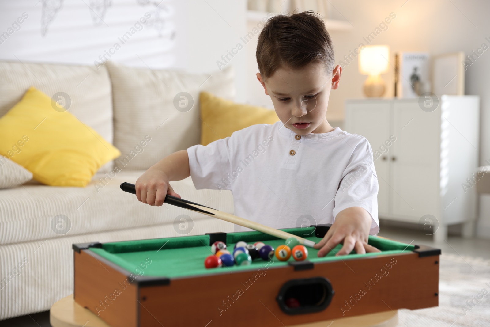 Photo of Cute little boy playing billiards at home