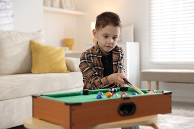 Photo of Cute little boy playing billiards at home