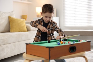 Photo of Cute little boy playing billiards at home