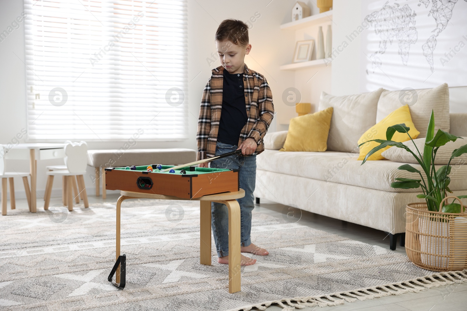 Photo of Cute little boy playing billiards at home