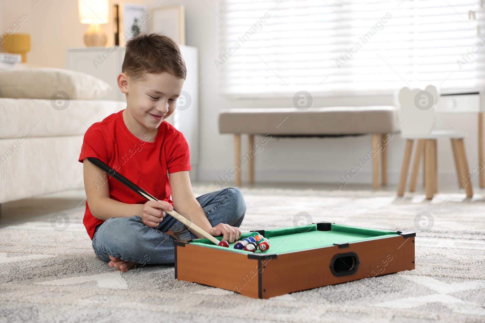 Photo of Cute little boy playing billiards at home