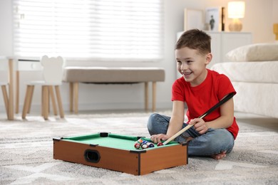 Photo of Cute little boy playing billiards at home