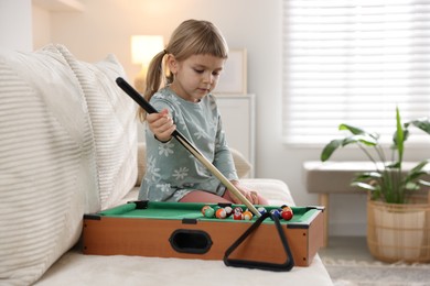 Cute little girl playing billiards at home