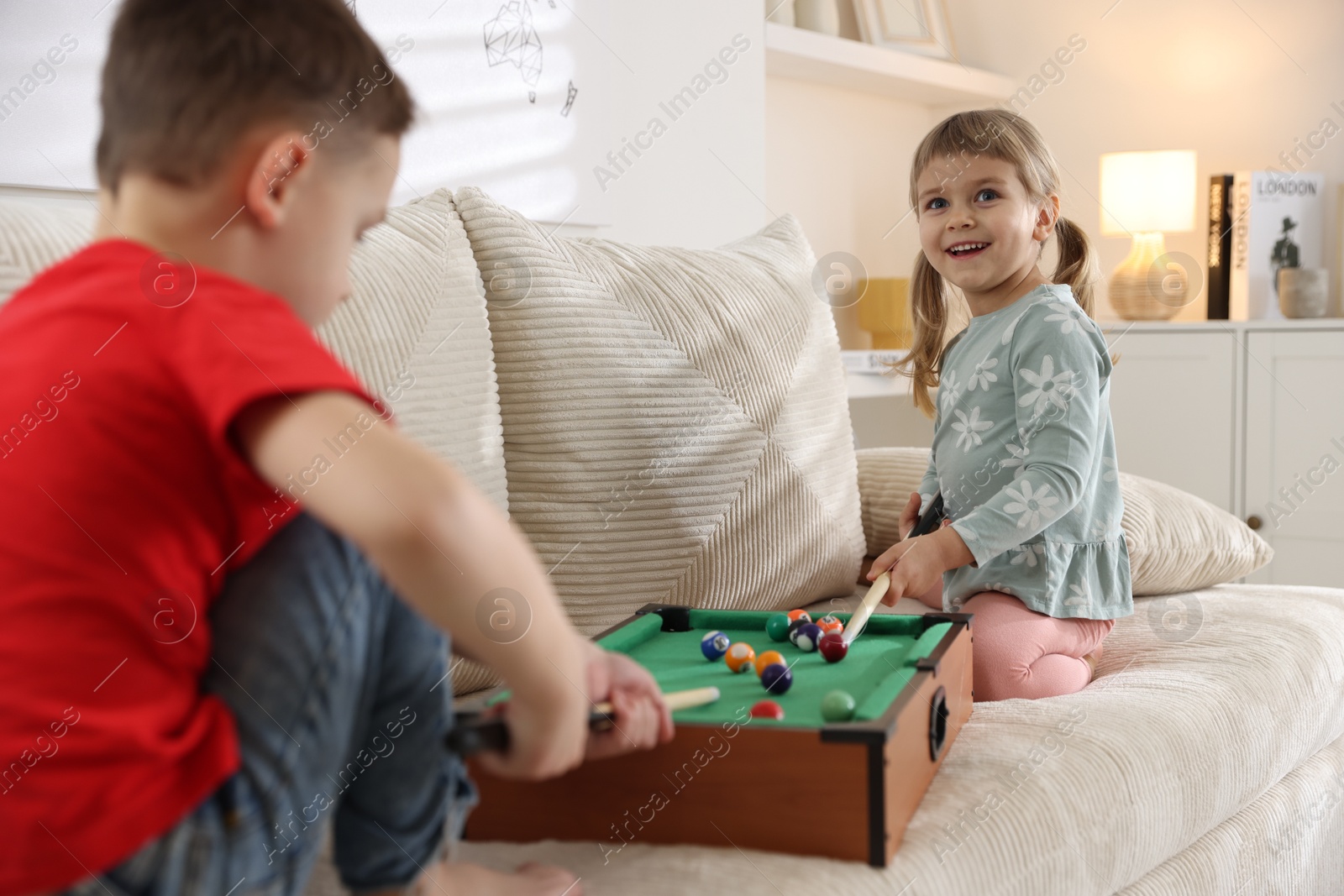 Photo of Cute brother and sister playing billiards at home