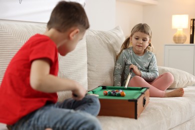 Photo of Cute brother and sister playing billiards at home