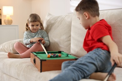 Photo of Cute brother and sister playing billiards at home