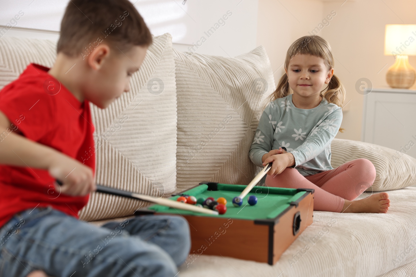 Photo of Cute brother and sister playing billiards at home