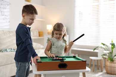 Photo of Cute brother and sister playing billiards at home