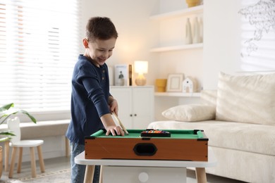 Photo of Cute little boy playing billiards at home