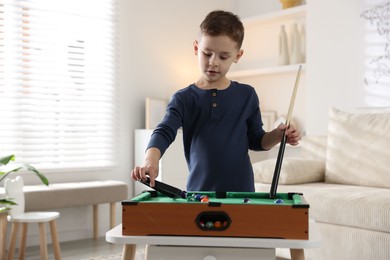 Photo of Cute little boy playing billiards at home