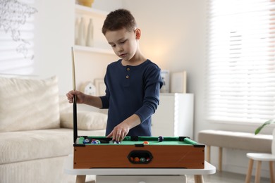 Photo of Cute little boy playing billiards at home