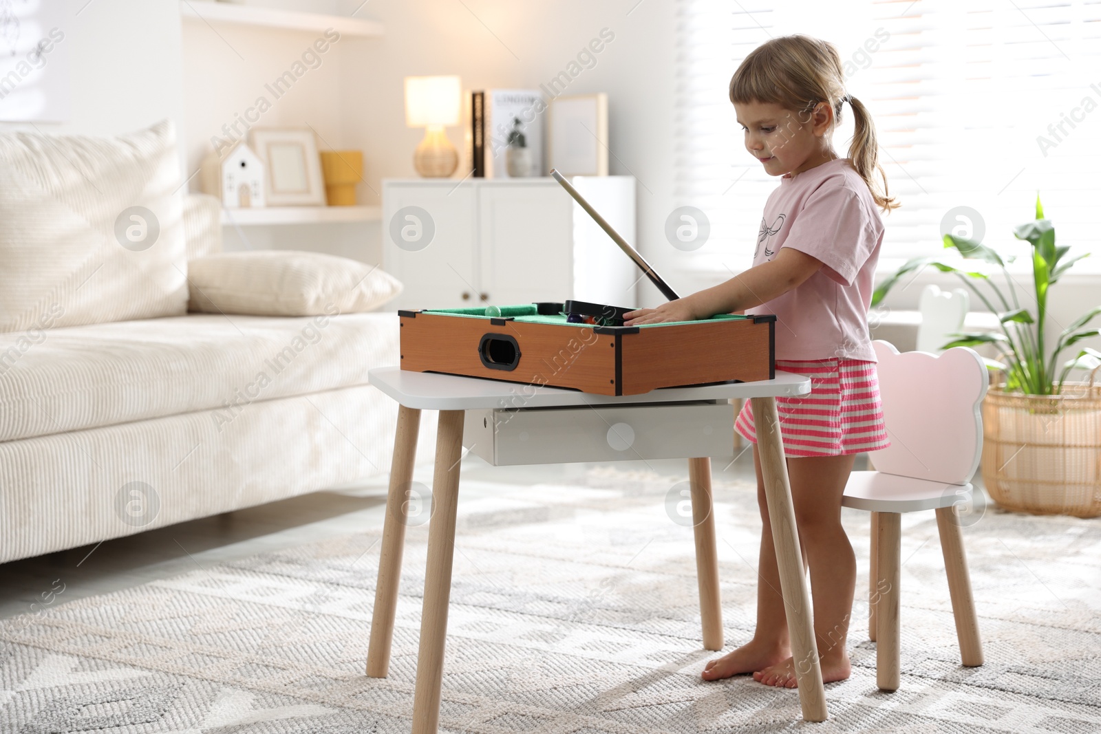 Photo of Cute little girl playing billiards at home