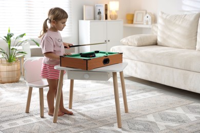 Photo of Cute little girl playing billiards at home