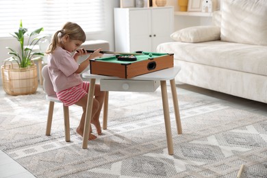 Photo of Cute little girl playing billiards at home