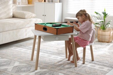 Photo of Cute little girl playing billiards at home