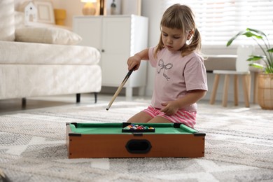 Cute little girl playing billiards at home