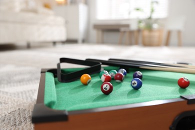 Photo of Many colorful billiard balls, triangle rack and cues on green table indoors, closeup