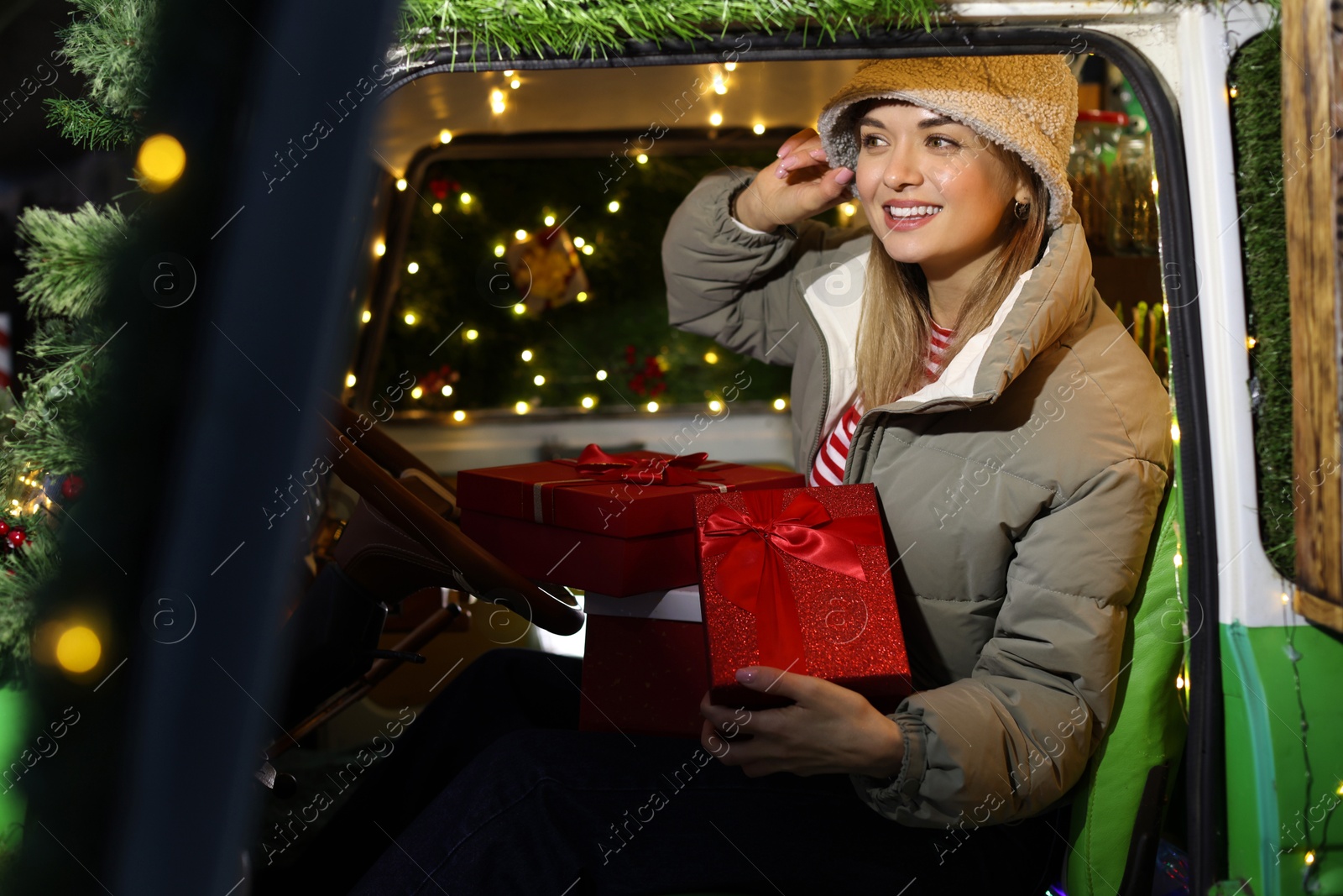 Photo of Happy woman with gifts in bus decorated for Christmas, view from outside