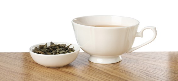 Photo of Refreshing green tea in cup and dry leaves on wooden table against white background