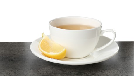 Photo of Refreshing green tea in cup and slice of lemon on grey textured table against white background