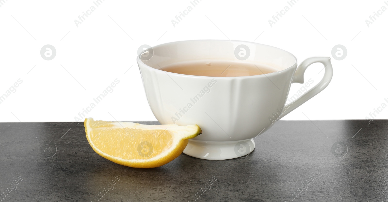 Photo of Refreshing green tea in cup and slice of lemon on grey textured table against white background