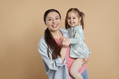 Photo of Portrait of happy mother and her cute little daughter on beige background