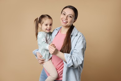 Photo of Portrait of happy mother and her cute little daughter on beige background