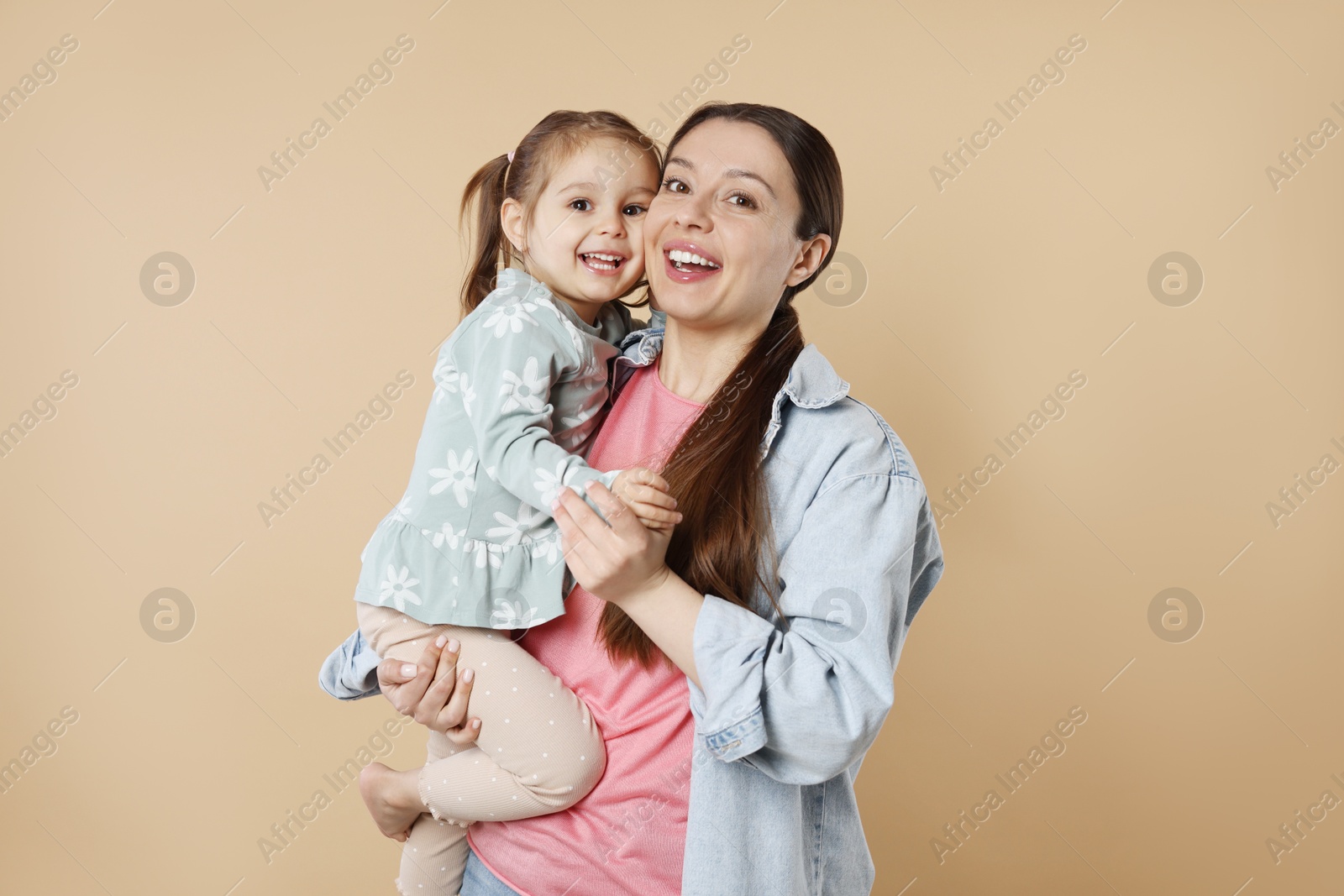 Photo of Portrait of happy mother and her cute little daughter on beige background