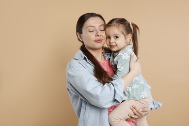 Photo of Portrait of happy mother and her cute little daughter on beige background, space for text