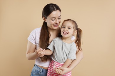 Photo of Portrait of happy mother and her cute little daughter on beige background