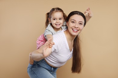 Photo of Portrait of happy mother and her cute little daughter having fun on beige background