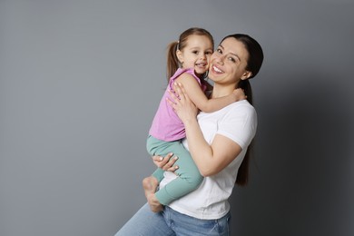 Photo of Portrait of happy mother and her cute little daughter on grey background, space for text