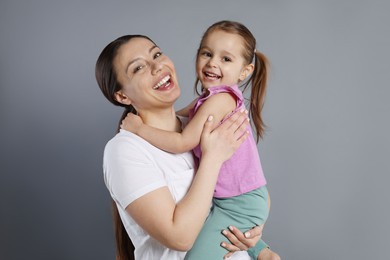 Photo of Portrait of happy mother and her cute little daughter on grey background