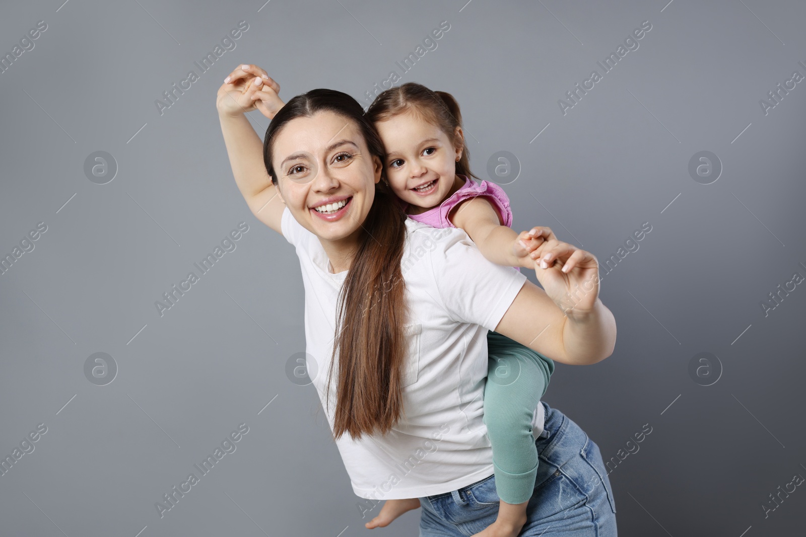 Photo of Portrait of happy mother and her cute little daughter on grey background