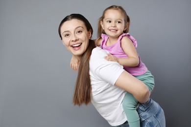 Photo of Portrait of happy mother and her cute little daughter on grey background, space for text