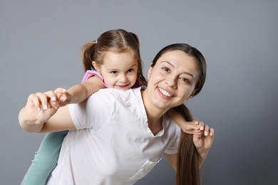 Photo of Portrait of happy mother and her cute little daughter on grey background