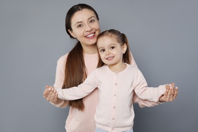 Photo of Portrait of happy mother and her cute little daughter on grey background