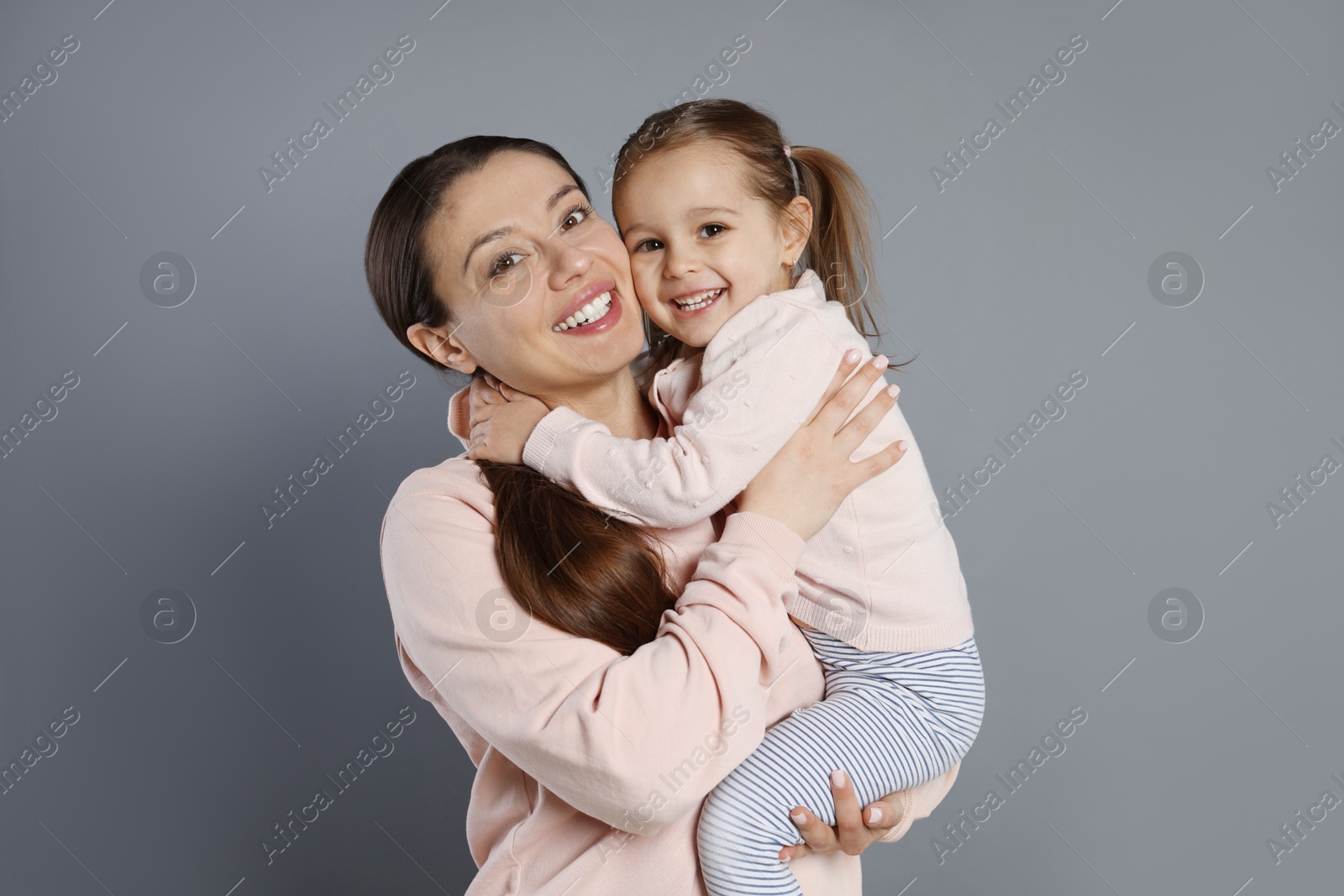 Photo of Portrait of happy mother and her cute little daughter on grey background