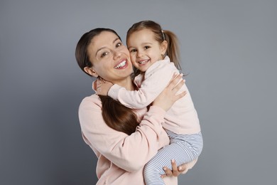 Photo of Portrait of happy mother and her cute little daughter on grey background