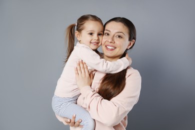 Photo of Portrait of happy mother and her cute little daughter on grey background