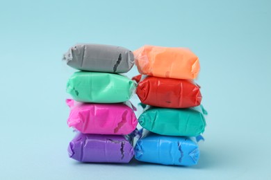 Photo of Different colorful play dough in packages on light blue background