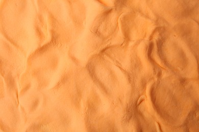 Photo of Orange play dough as background, top view