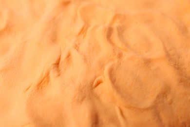 Photo of Bright orange play dough as background, closeup