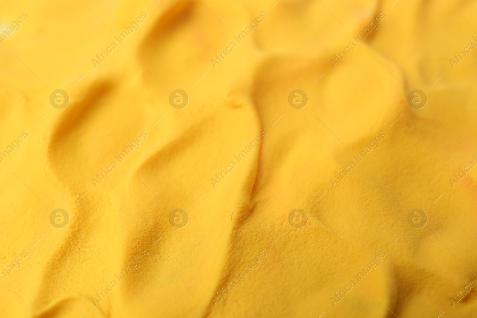 Photo of Bright yellow play dough as background, closeup