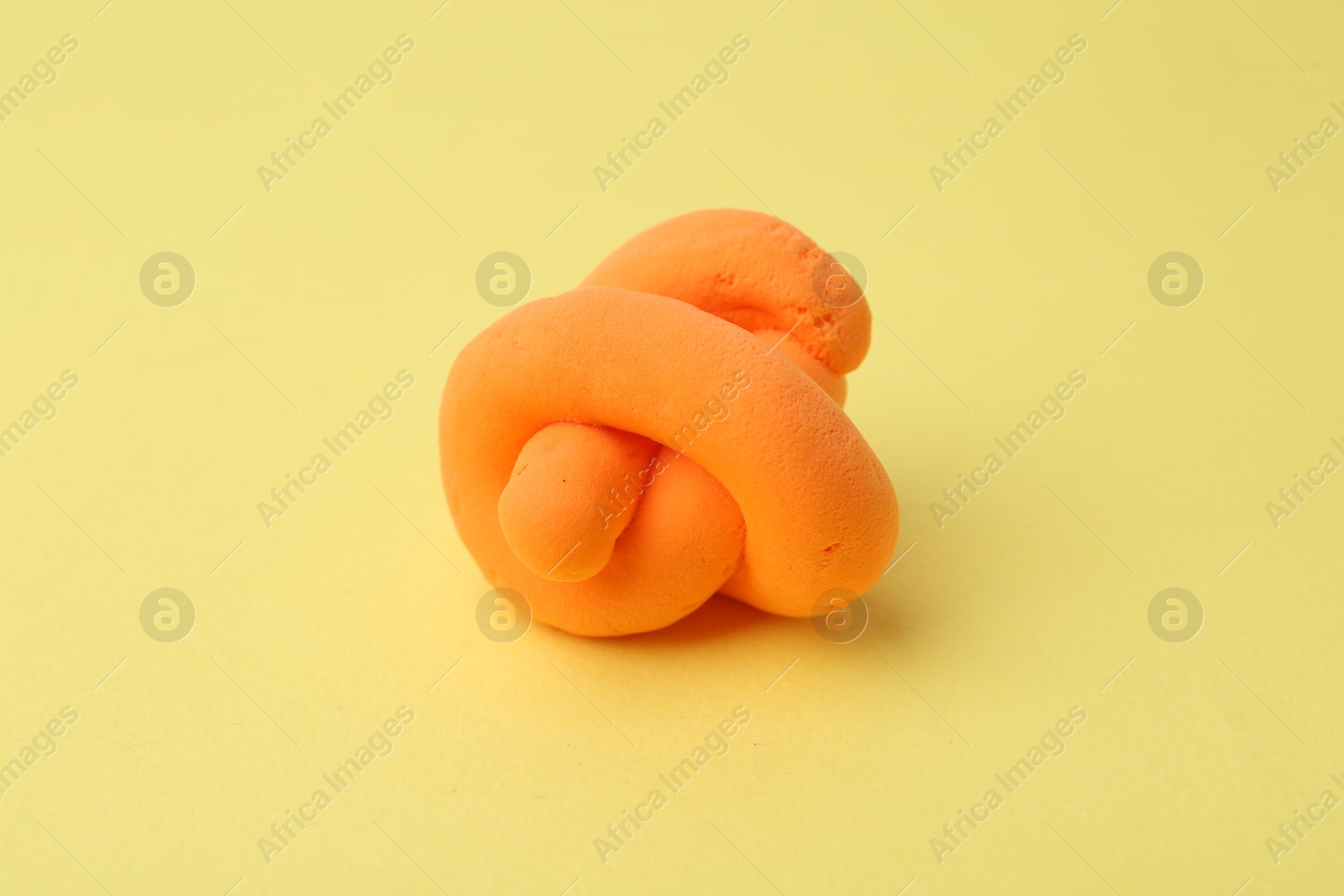 Photo of Bright orange play dough on yellow background