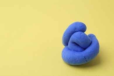 Photo of Bright blue play dough on yellow background, space for text